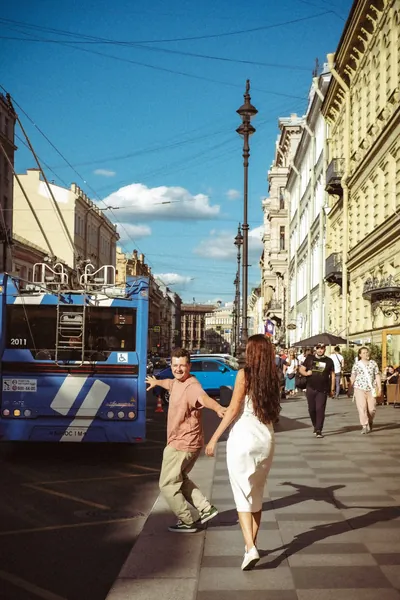O casal numa larga avenida da cidade, com um trólei ao fundo — Olesia Shelkovenko