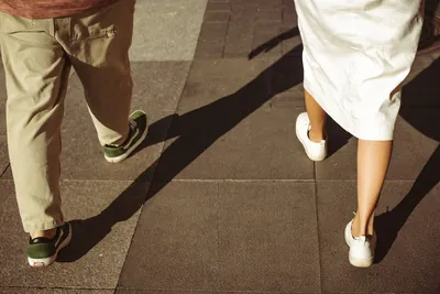 As pernas do casal a caminhar e as sombras longas no passeio — Olesia Shelkovenko